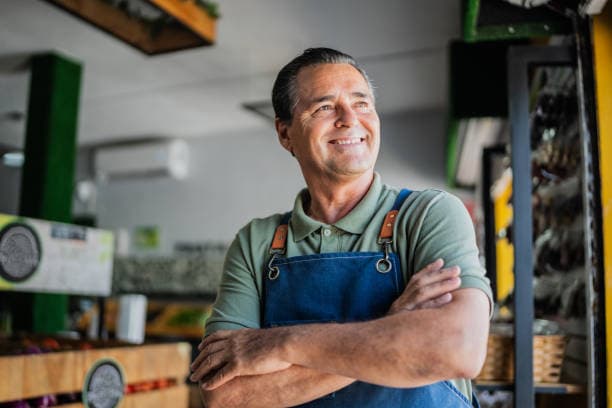 A smiling shop owner standing confidently in his store