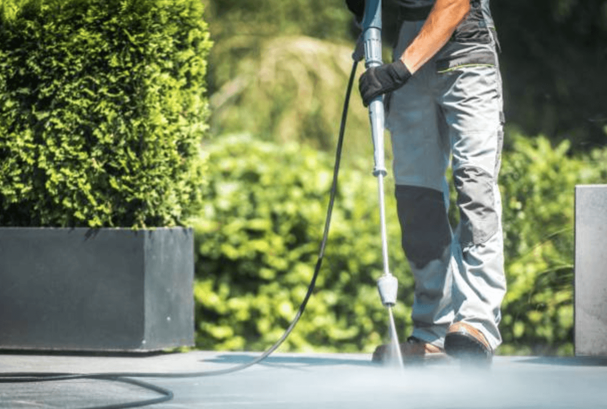 A power washer cleaning a stone patio outside a home